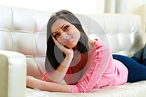 Middle-aged smiling woman lying on the sofa