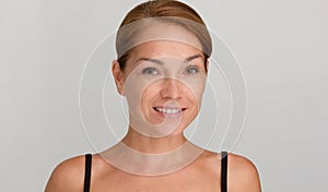 Middle aged smiling woman with reddish hair and calm look looking at camera on grey background