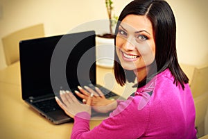 Middle-aged smiling woman using laptop