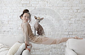 Middle aged sporty woman having fun with her dog xoloitzcuintli indoors