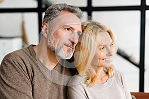 Middle-aged spouses sits on the sofa at home and look aside at one way