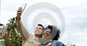 Middle-aged tourist diverse couple taking a selfie in a city. Heterosexual couple on vacation