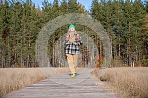 Middle aged tourist hiker woman walking ecotrope in natural Scandinavian park with pine trees.