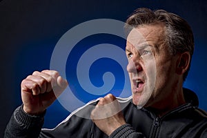 A middle aged white man in boxing stance on a black and blue background
