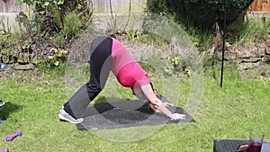 A middle aged white woman doing a mixture of aerobic and anaerobic exercises in her garden