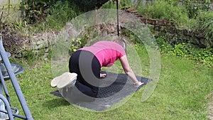 A middle aged white woman doing a mixture of aerobic and anaerobic exercises in her garden