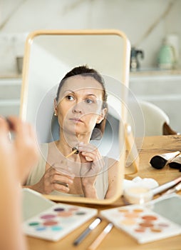 Middle-aged woman applying liquid foundation on her face