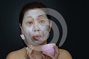 A middle-aged woman Asians are happy with a face mask for skin care.The concept of skin care and beauty