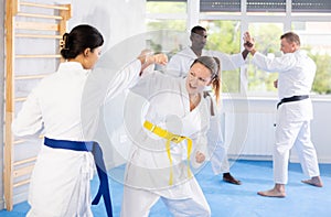 Middle-aged woman attendee of karate classes fighting with her opponent in sports hall