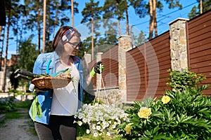 Middle-aged woman in backyard with gardening tools and blooming petunia in pot