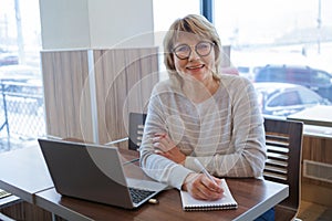 Middle-aged woman business in workplace in cafe, office, she`s working on her laptop