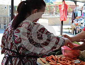 Middle-aged woman buys vegetables at a green market