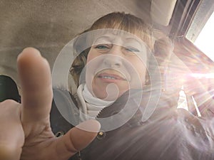 Middle aged woman in a car taking selfie while enjoying a drive. Female mature driver posing inside car. Funny happy