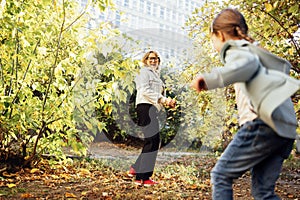 Middle aged woman in casual clothes and her little cute granddaughter playing game at autumn park. Smiling grandmother and cute