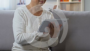 Middle-aged woman chatting in social network on tablet, connecting with family