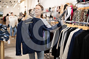 Middle-aged woman choosing convenient blazer in clothing store