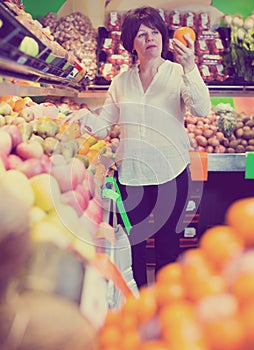 Middle aged woman choosing fruits