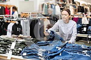 Middle-aged woman choosing jean skirt in clothing store