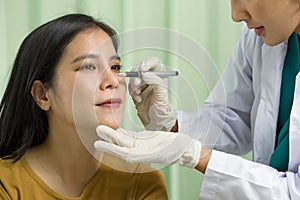 Middle aged woman on consultation at surgeon, doctor making marks on female patient\'s face. Close