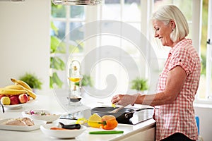 Middle Aged Woman Cooking Meal In Kitchen