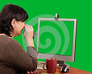 Middle-aged woman crying looking into a chroma key screen monitor.