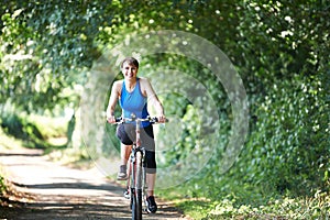 Middle Aged Woman Cycling On Country Road