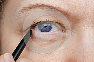 Middle-aged woman does corrective eye makeup to correct the drooping eyelid. Ptosis is a drooping of the upper eyelid, lazy eye.