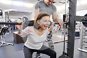 Middle-aged woman doing sports exercise in fitness center. Personal gym trainer assisting mature woman. Health fitness sport age