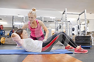 Middle-aged woman doing sports exercise in fitness center. Personal gym trainer assisting mature woman. Health fitness sport age