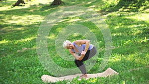 Middle-aged woman doing yoga outdoors in Revolved Chair Pose. Parshva (Side)