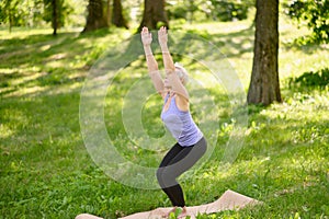Middle-aged woman doing yoga outdoors in Revolved Chair Pose. Parshva & x28;Side& x29;