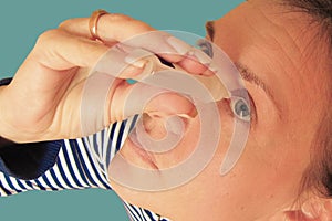Middle aged woman drops eyes. Macro closeup image of face. Medical procedure at home. Girl holding eyedropper bottle and dropping
