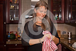 Middle aged woman drying hands with a kitchen towel.