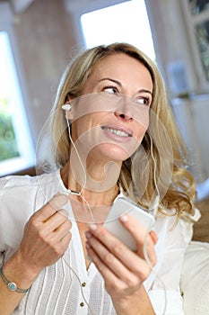 Middle-aged woman with earphones talkintg on the phone