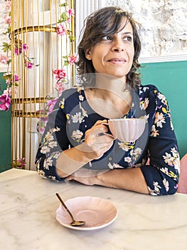 A middle-aged woman enjoying a cup of coffee in a cute Coffee Shop