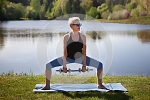 Middle aged woman enjoys workout, exercises, training body in midst of nature, dedicating herself to healthy lifestyle