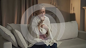 Middle-Aged Woman Experiencing a Coughing Fit While Seated on a Sofa Indoors