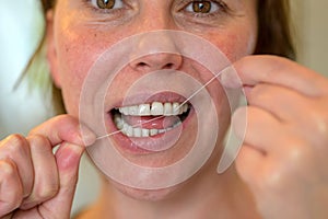 Middle-aged woman flossing her teeth