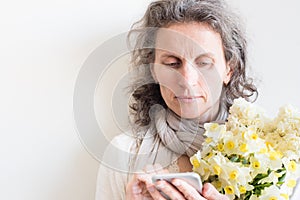 Middle aged woman with flowers and smart phone