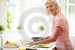 Middle Aged Woman Following Recipe On Digital Tabl