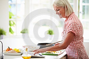 Middle Aged Woman Following Recipe On Digital Tablet