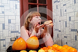 Middle-aged woman with fruit and sausages at the table in the room