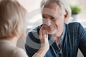 Middle aged woman gently stroking face of mature smiling man