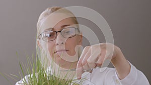 A middle-aged woman, with glasses on his eyes, mows the lawn with manicure scissors.