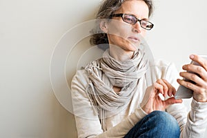 Middle aged woman with glasses and smart phone