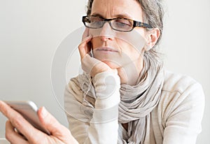 Middle aged woman with glasses and smart phone