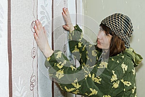 Middle-aged woman glues wallpaper