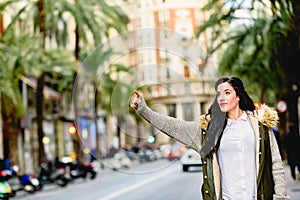Middle-aged woman hailing a taxi with her hand raised in the street