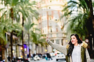 Middle-aged woman hailing a taxi with her hand raised in the street