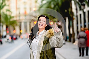 Middle-aged woman hailing a taxi with her hand raised in the street